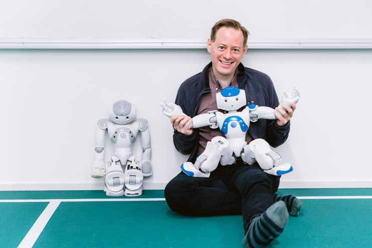 Prof Fredrik Heintz sitting on the floor with a robot on his lap